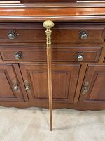 Full view of wooden cane leaning against sideboard