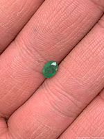 Emerald on fingertip, showing size and oval faceting