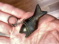fish-shaped wooden bottle opener resting on hand, full view