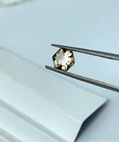 Tweezers holding hexagonal smoky topaz angled view showing color and faceting