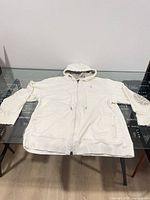 Front view of light cream Air Jordan zip hoodie laid flat on glass table