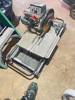 Full view of Brutus tile saw on metal frame showing sliding tray and overall wear