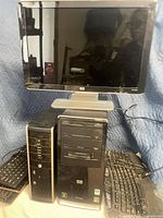 Front view of HP monitor atop two desktop PCs with keyboards visible