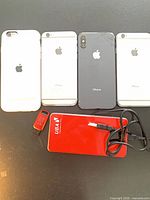 Group shot of four iPhones, UBA power bank, red USB flash drive, black cable
