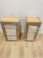 Two shrink-wrapped white upper cabinets standing side by side