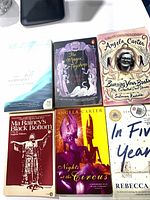 Six paperback books laid out showing full covers