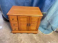 Front view showing cabinet with three drawers and louvered doors