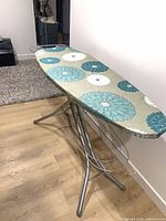Full view of oversized ironing board with floral cover and metal frame