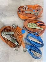Coiled orange and blue ratchet straps showing hooks and ratchets