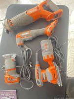 All four Ridgid tools on table: reciprocating saw, oscillating tool, router, sander