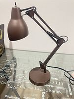 Side view of brown metal swing-arm desk lamp fully extended