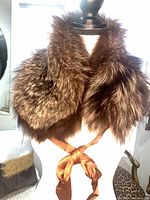 Full view of brown fur scarf draped on mannequin showing ribbon tie