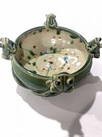 Top view of green ceramic bowl with four frog heads and speckled interior