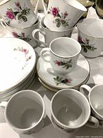 Stack of floral saucers with multiple matching cups showing pattern and gold rims