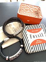 Both bracelets, dust bag, and open Fossil tin box displayed