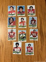 Fronts of eleven 1975 Topps Denver Broncos cards laid out on wood surface