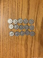 Obverse view of 15 1967 Canada 5-cent rabbit coins arranged on wood surface