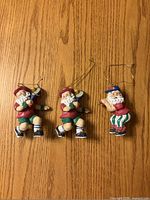 Front view of three Sport Santa resin ornaments