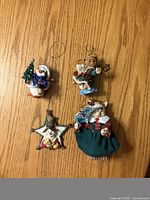 Four assorted resin Christmas ornaments arranged on wood surface