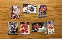 Front view of seven Johnny Gaudreau hockey trading cards laid out on wood surface