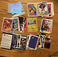 Spread of approx 75 assorted trading cards on wooden surface