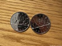 Obverse view of both coins showing Voyageur canoe design with dates 1981 and 1985
