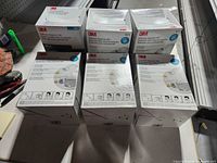 Six sealed 3M respirator cartons on table