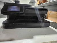 Front view showing HP Photosmart 7510 printer, touchscreen lit, paper output tray, overall condition