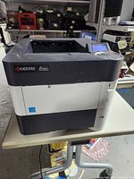Front angled view of Kyocera printer showing brand and model badge
