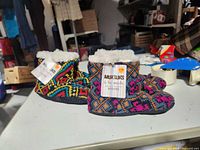 Two pairs of Muk Luks slipper booties on table