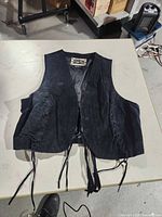Front view of black leather vest with lace-up sides and ties