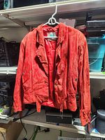 Front view of red leather fringe coat hanging open showing belt and lining