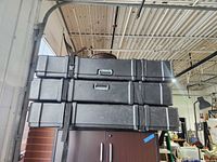 Stack of three black Showtopper rolling cases on cabinet