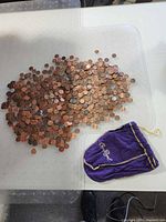 Large pile of U.S. pennies next to empty Crown Royal bag