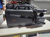 Left side of Magnavox camcorder showing MAGNAVOX logo, Hi8 HQ and CCD markings, carrying handle and attached bag behind