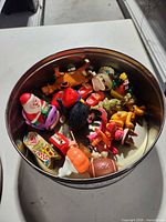 Open cookie tin showing assortment of plastic wind-up toys