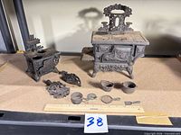 Both toy stoves with all loose accessories laid out for scale