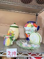 All four items on shelving: biscotti jar, urn/vase, creamer, glass dish