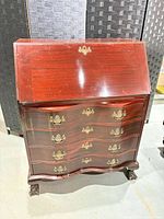 Full view closed showing drop-front and four serpentine drawers with brass hardware