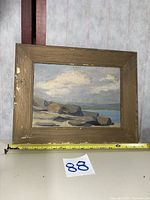 Front view of framed seascape painting with measuring tape