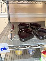 Shelf view showing four triangular ruby glass dishes and ruby-handled server