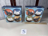 Two boxed sets each showing four hen design plates