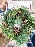 Front view of wreath showing greenery, pinecones and berry accents