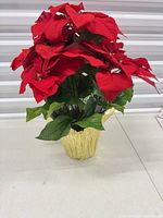 Front view of artificial poinsettia showing red blooms, green leaves, gold foil pot