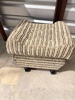 Overall view of ottoman showing striped fabric and caster base