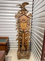 Full view of carved longcase cuckoo clock showing entire case, dial, pendulum window and base carvings