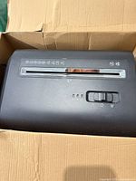 Top view of shredder in box showing feed slot and controls