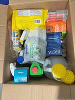 Box view showing Swiffer Sweeper cloths, Brita filter box, gallon jug cleaner, Osram bulb, sponges, green cleaner bottle, drinking straws, spray bottle