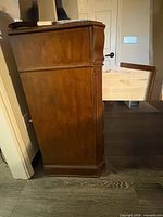 Left side view showing wood grain, fluted panel, bracket foot