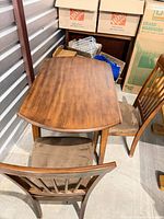 round solid wood dining table with two chairs visible